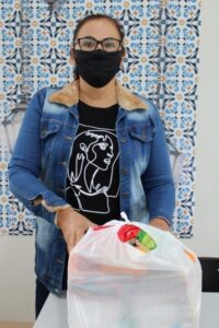 Secretária Liziane com cesta básica distribuída aos estudantes carentes da Rede Pública Municipal de Ensino